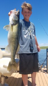 Boy fisher on a boat with catch