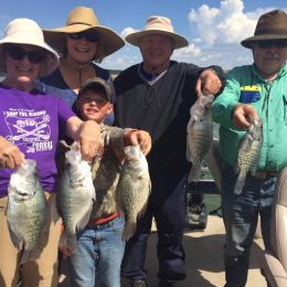 Family of 5 on a fishing boat holding catch